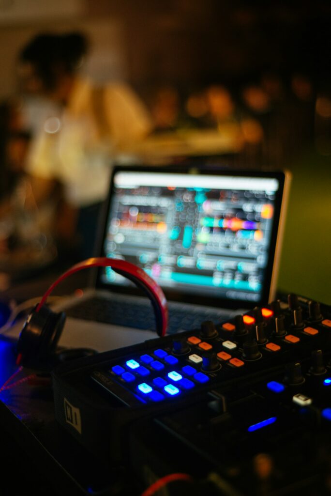 Selective focus vertical shot of a disc jockey sound mixer and a laptop screen at night club